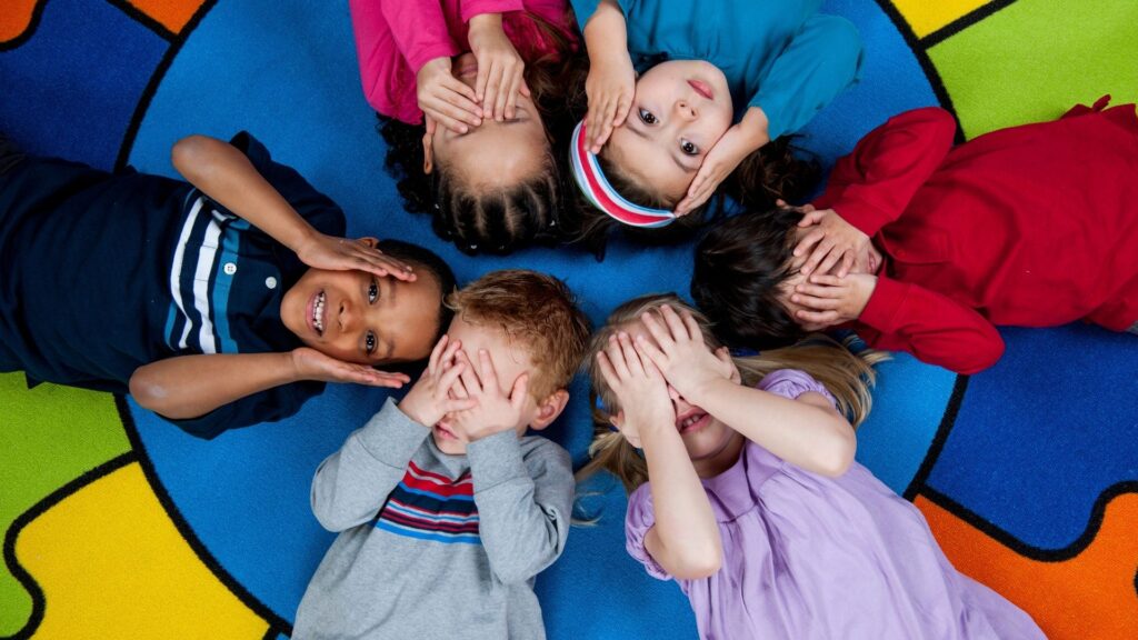 students lying on a rainbow carpet